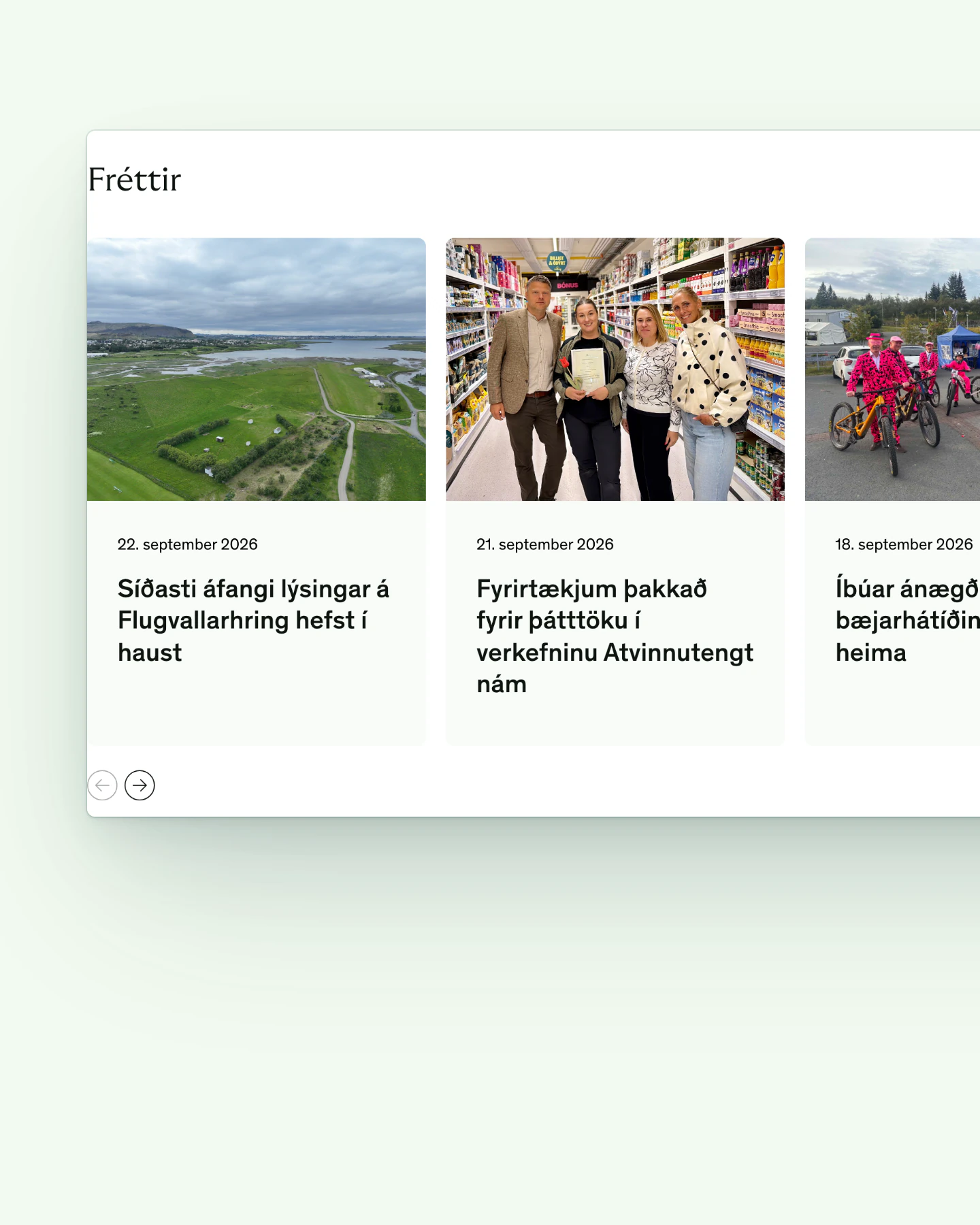 Close crop of the news section on the Mosfellsbær homepage, headed "Fréttir". Three cards sit side by side: an aerial view of green fields and coastal wetland, four smiling people walking down a supermarket aisle with one holding a folder, and children in pink outfits on bicycles. Each carries a September 2026 date, a headline, and circular arrow buttons below.